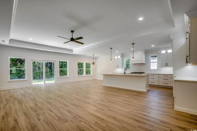 205 Brush Ct, Little River, SC 29566 - unfurnished living room featuring a tray ceiling, ornamental molding, a sink, ceiling fan, and light wood-style flooring