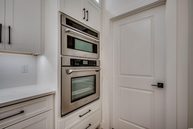205 Brush Ct, Little River, SC 29566 - kitchen featuring decorative backsplash, double oven, light stone countertops, and white cabinetry
