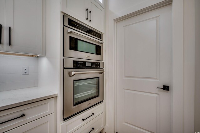 205 Brush Ct, Little River, SC 29566 - kitchen with stainless steel double oven, light stone counters, backsplash, and white cabinetry