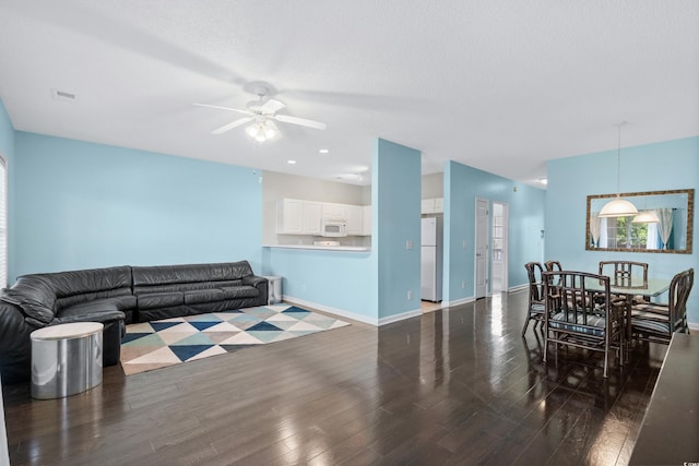 living room featuring ceiling fan and dark wood-type flooring