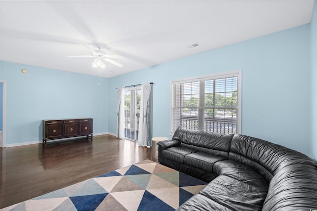 living room with ceiling fan and dark wood-type flooring