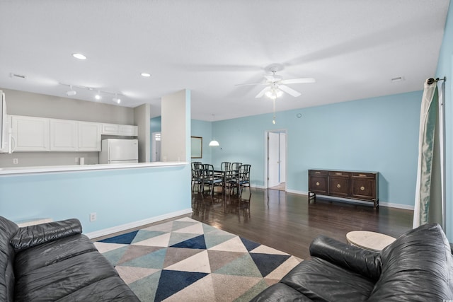 living room featuring rail lighting, ceiling fan, and dark wood-type flooring