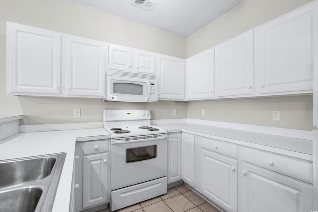 kitchen featuring white appliances, sink, light tile patterned floors, a textured ceiling, and white cabinetry