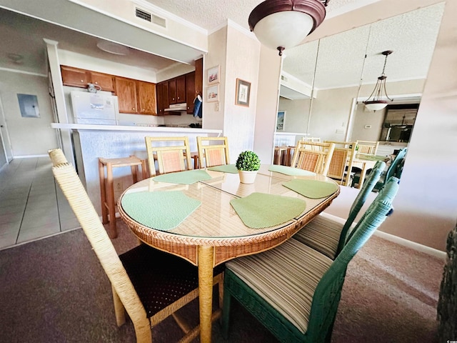 tiled dining area with ornamental molding and a textured ceiling