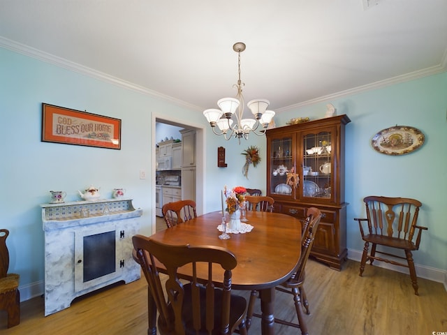 dining space with light hardwood / wood-style floors, crown molding, and a chandelier