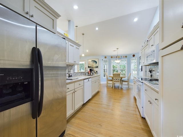 kitchen featuring hanging light fixtures, backsplash, light stone countertops, light wood-type flooring, and white appliances