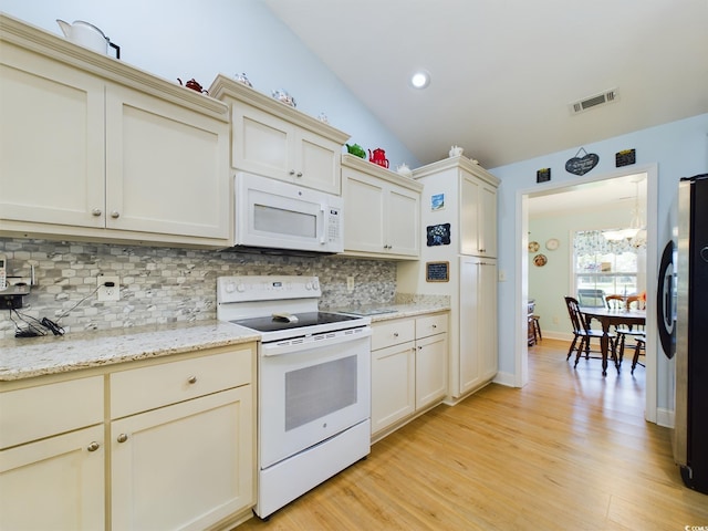 kitchen with vaulted ceiling, cream cabinets, white appliances, and light hardwood / wood-style floors