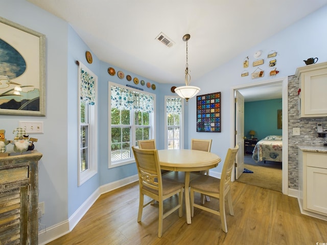 dining space with light hardwood / wood-style floors and vaulted ceiling