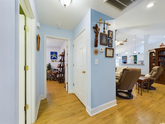 hallway featuring light hardwood / wood-style floors and lofted ceiling