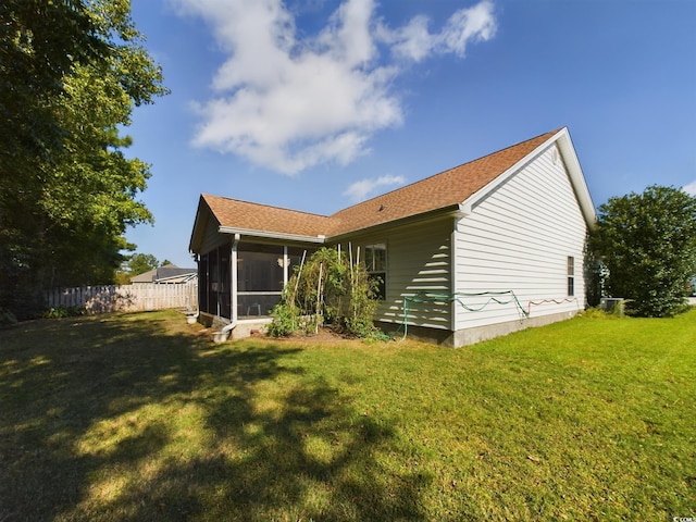 rear view of house featuring a yard and a sunroom