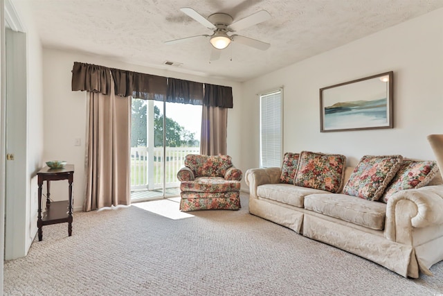 carpeted living room with ceiling fan and a textured ceiling