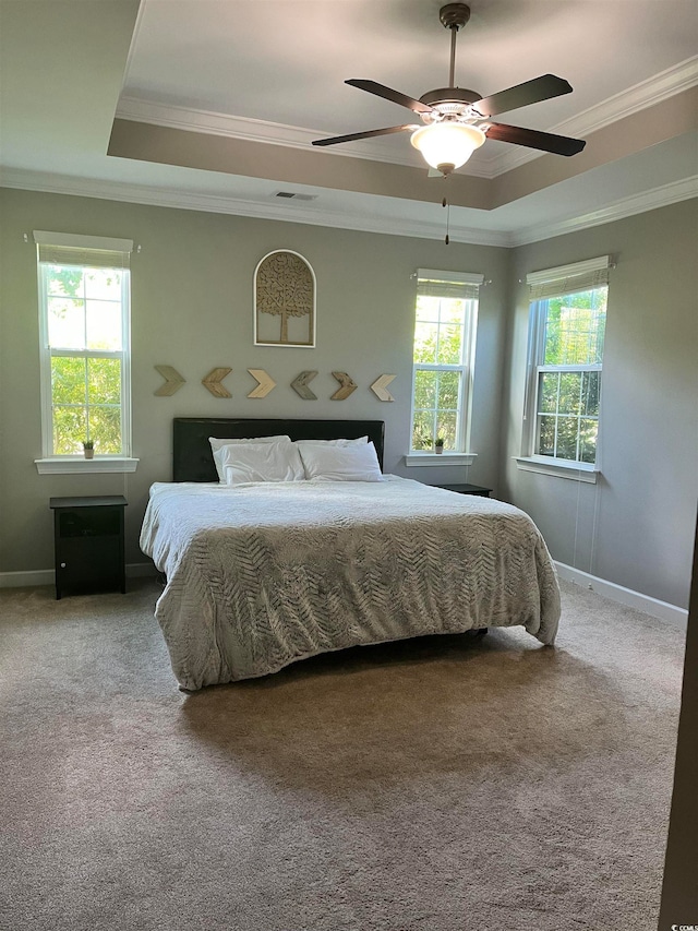 carpeted bedroom featuring a tray ceiling, crown molding, and ceiling fan