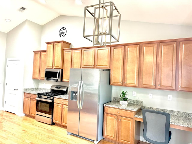 kitchen with light wood-type flooring, stainless steel appliances, light stone counters, decorative light fixtures, and vaulted ceiling