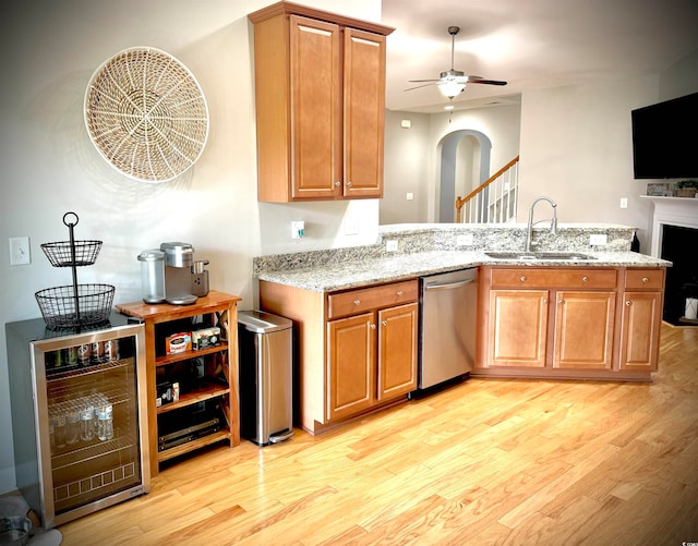 kitchen featuring light stone counters, light hardwood / wood-style flooring, dishwasher, wine cooler, and sink