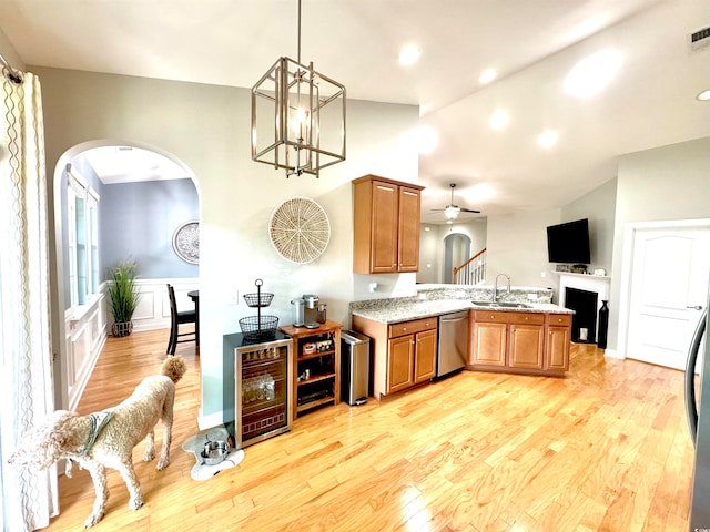 kitchen with kitchen peninsula, stainless steel dishwasher, decorative light fixtures, light wood-type flooring, and ceiling fan with notable chandelier