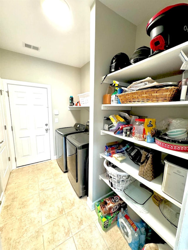 clothes washing area featuring washer and dryer and light tile floors