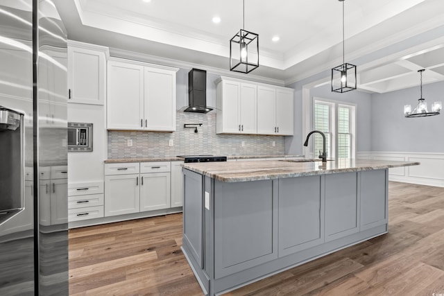 kitchen with stainless steel refrigerator with ice dispenser, wall chimney exhaust hood, and white cabinets