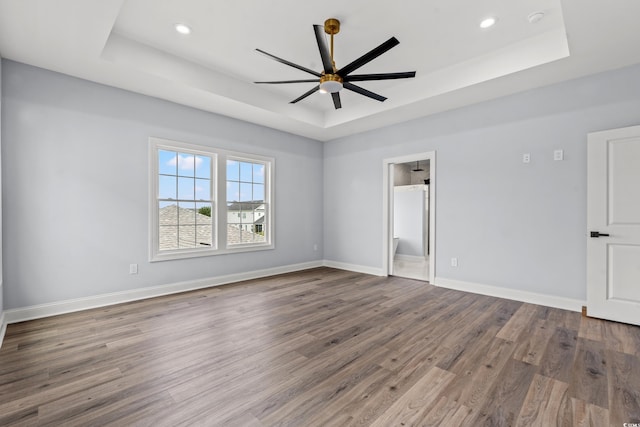 spare room featuring ceiling fan, hardwood / wood-style floors, and a tray ceiling