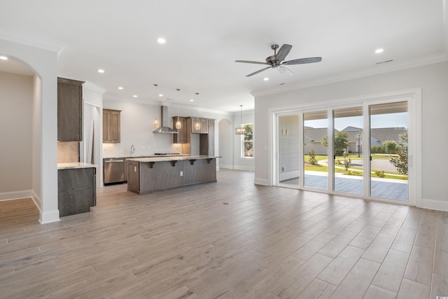 unfurnished living room with ceiling fan, ornamental molding, and light hardwood / wood-style flooring