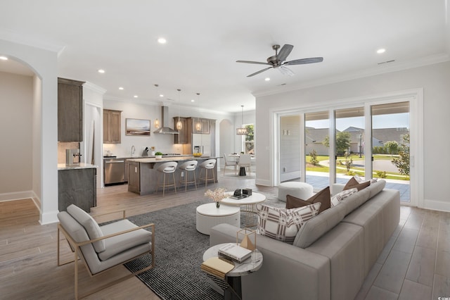 living room featuring ornamental molding, ceiling fan, and light hardwood / wood-style flooring