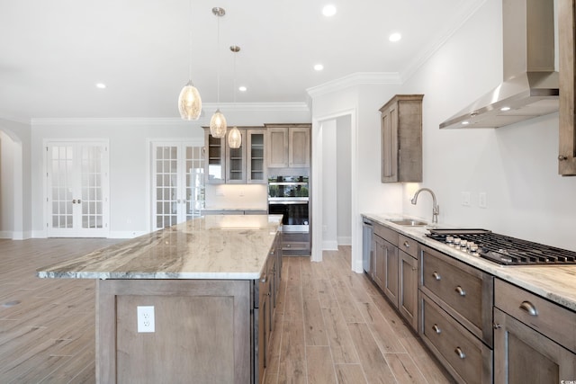 kitchen featuring a kitchen island, appliances with stainless steel finishes, sink, wall chimney exhaust hood, and french doors