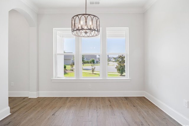 unfurnished dining area with a notable chandelier, crown molding, and light hardwood / wood-style flooring