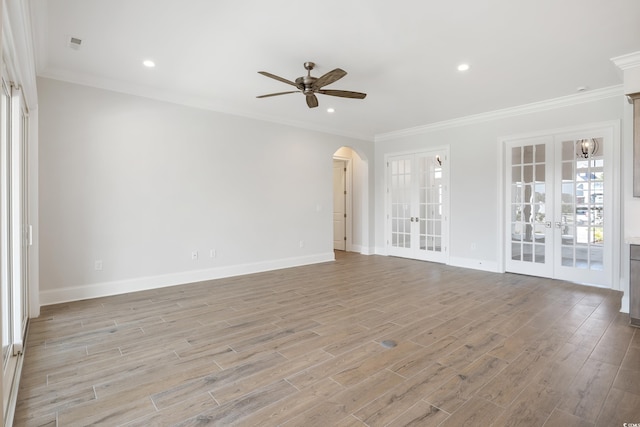 empty room with french doors, ceiling fan, ornamental molding, and light wood-type flooring