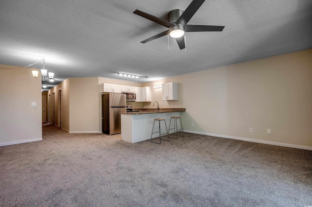 unfurnished living room with ceiling fan with notable chandelier, light carpet, and a textured ceiling