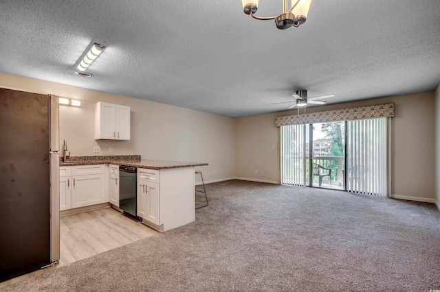 kitchen featuring white cabinets, dishwasher, ceiling fan with notable chandelier, stainless steel fridge, and kitchen peninsula