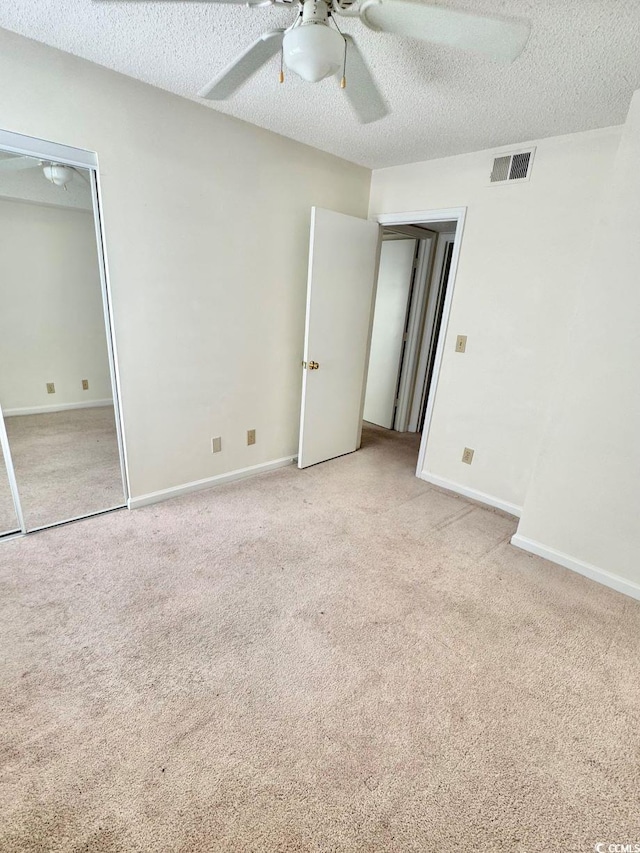 unfurnished bedroom with a textured ceiling, ceiling fan, and light carpet