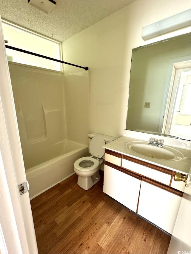 full bathroom with vanity, bathtub / shower combination, hardwood / wood-style flooring, toilet, and a textured ceiling