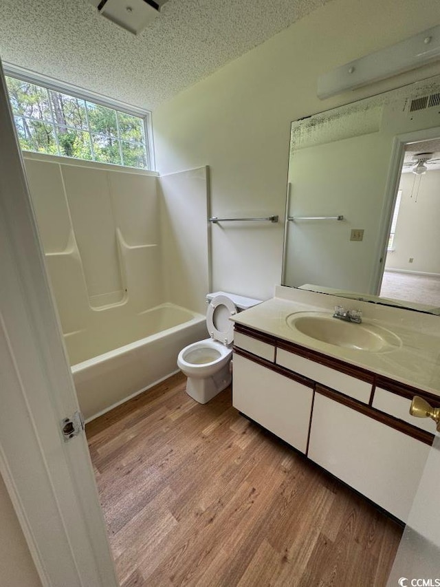 full bathroom with toilet, vanity, a textured ceiling, and hardwood / wood-style flooring