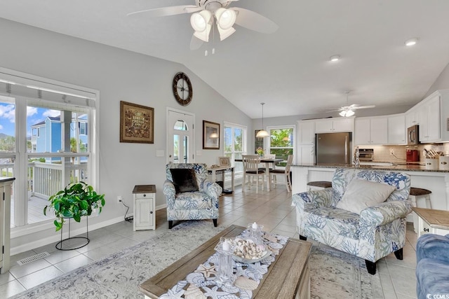 living room with ceiling fan, lofted ceiling, and light tile patterned floors