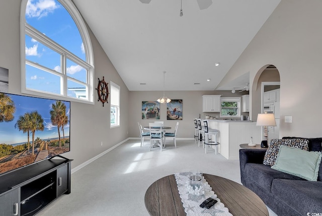 living room featuring ceiling fan, high vaulted ceiling, and light carpet