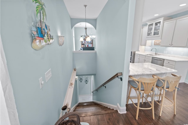 staircase featuring sink, hardwood / wood-style floors, and a notable chandelier