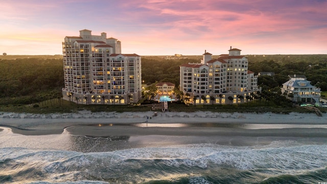 outdoor building at dusk featuring a view of the beach and a water view