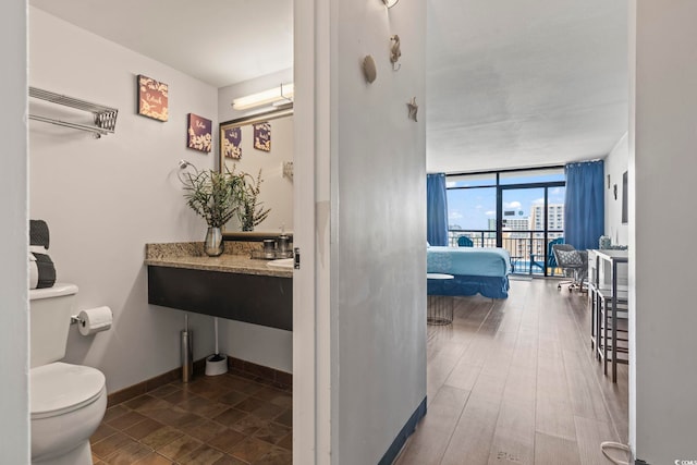 bathroom with hardwood / wood-style flooring, toilet, and floor to ceiling windows