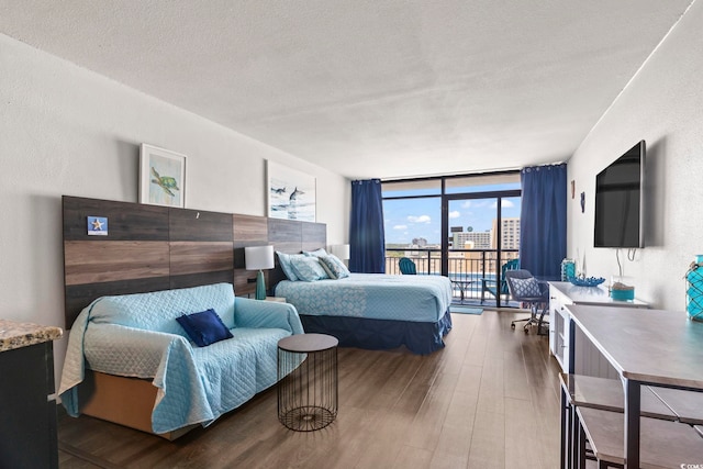 bedroom featuring hardwood / wood-style flooring, a wall of windows, a textured ceiling, and access to outside