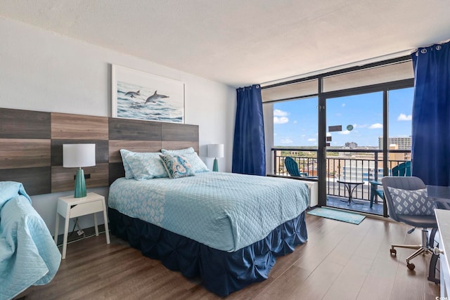 bedroom with hardwood / wood-style floors, expansive windows, access to exterior, and a textured ceiling