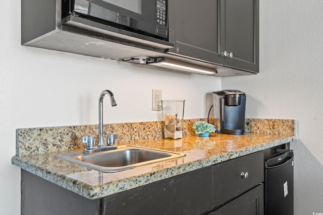 kitchen featuring light stone counters and sink