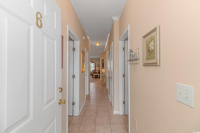 corridor featuring light tile patterned flooring and crown molding