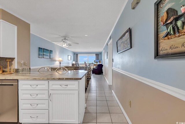 kitchen with ceiling fan, stainless steel dishwasher, light tile floors, ornamental molding, and white cabinetry