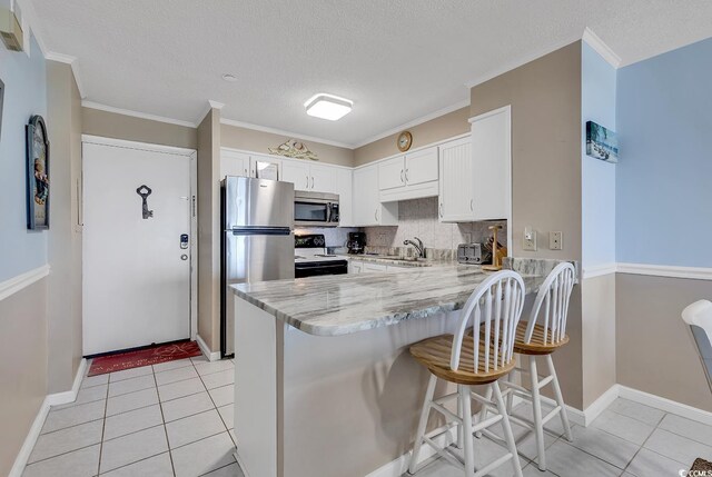 kitchen with kitchen peninsula, stainless steel appliances, backsplash, a kitchen bar, and light tile floors