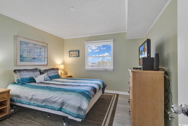 bedroom featuring hardwood / wood-style floors, ornamental molding, and a textured ceiling