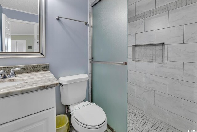 bathroom with vanity with extensive cabinet space, walk in shower, toilet, and crown molding