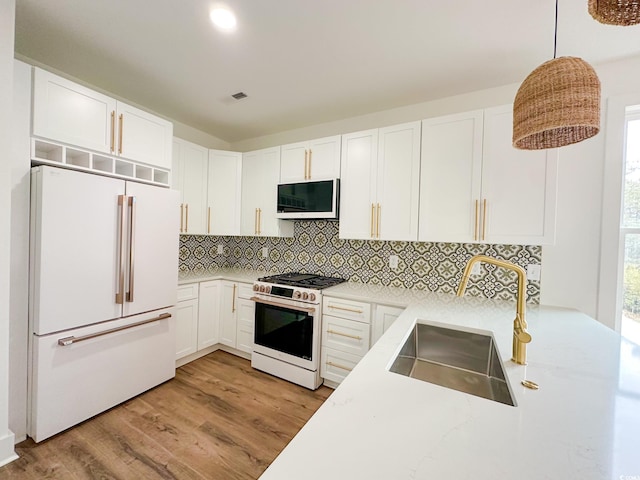 kitchen featuring white appliances, decorative backsplash, hanging light fixtures, white cabinetry, and a sink