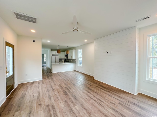 unfurnished living room with ceiling fan, light wood-style flooring, and visible vents