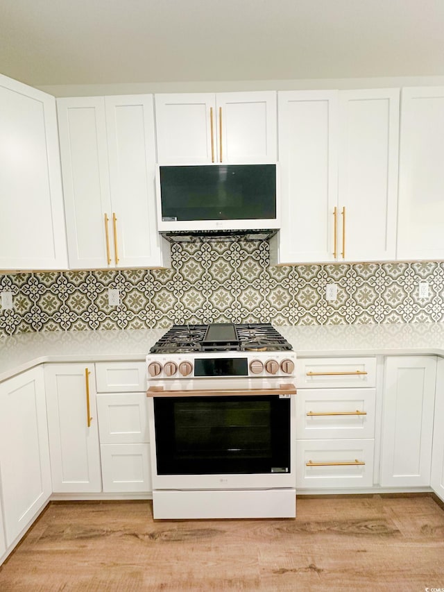 kitchen with range hood, white cabinets, light countertops, and gas range