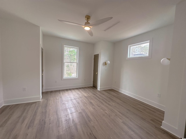 empty room with ceiling fan, baseboards, a wealth of natural light, and wood finished floors