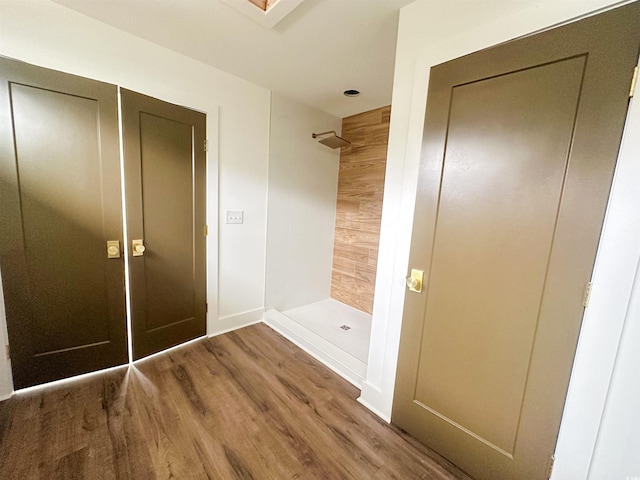 bathroom with baseboards, a shower stall, and wood finished floors